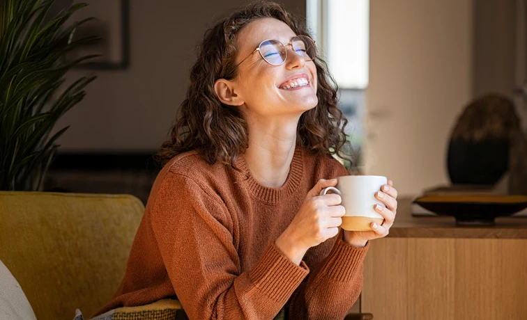 Mujer sonriendo mientras toma una bebida caliente