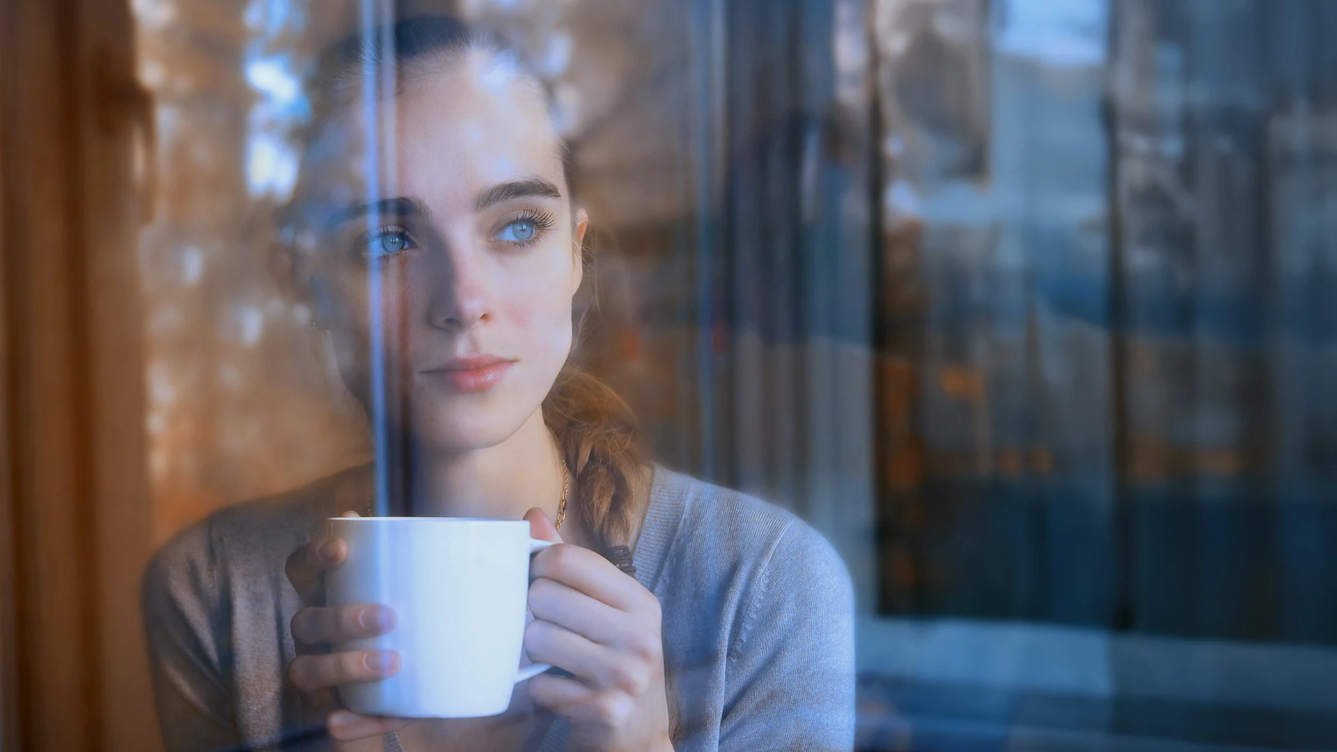 Mujer sosteniendo una taza de té junto a la ventana