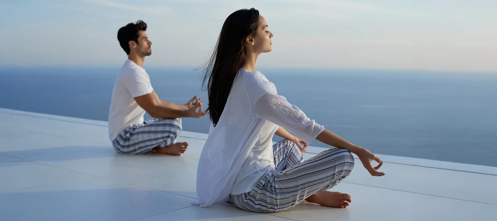 Pareja meditando frente al mar